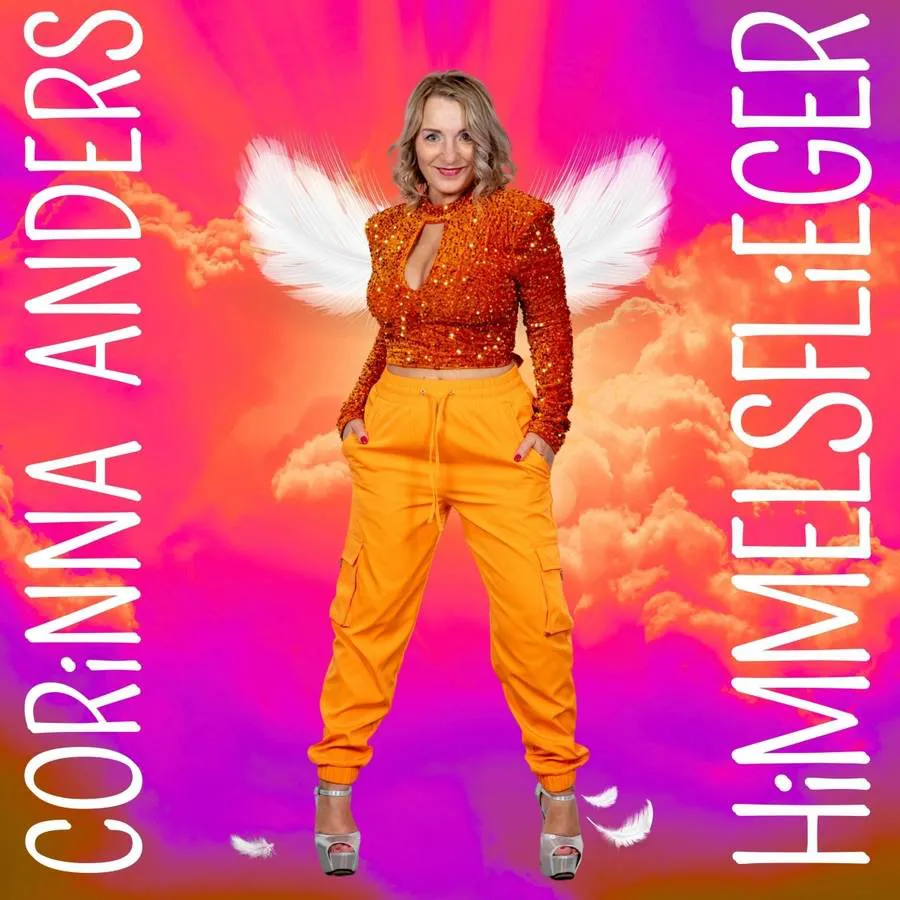 Eine Frau in orangefarbenen Hosen und einem glitzernden Oberteil mit Engelsflügeln steht da; der Text lautet „Corinna Anders Himmelsflieger“.