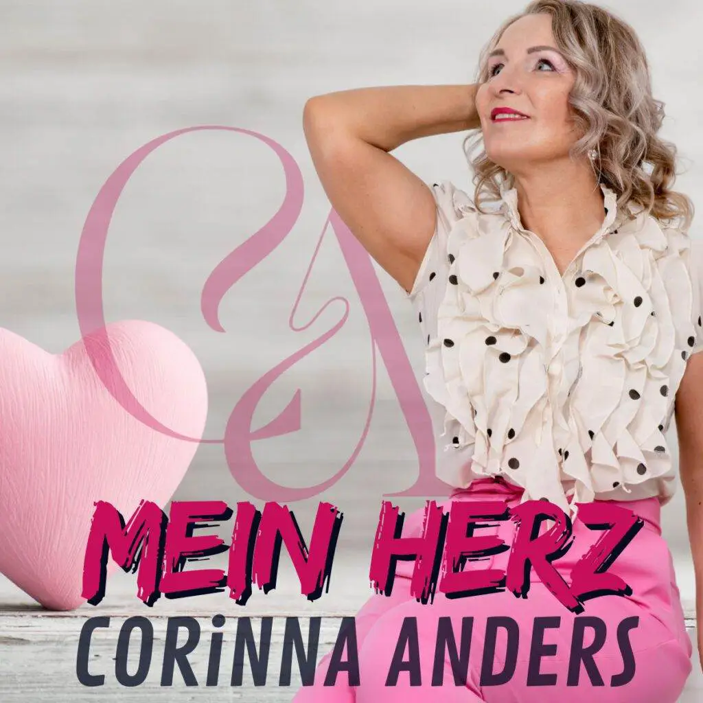 Eine Frau mit lockigem Haar in einer cremefarbenen Rüschenbluse und rosafarbenen Hosen posiert neben einem großen rosafarbenen Herz und verkörpert den Geist von „Mein Herz“. Der Hintergrund ist hellgrau, während der markante Text den Charme und das Talent der Schlagersängerin Corinna Anders hervorhebt.
