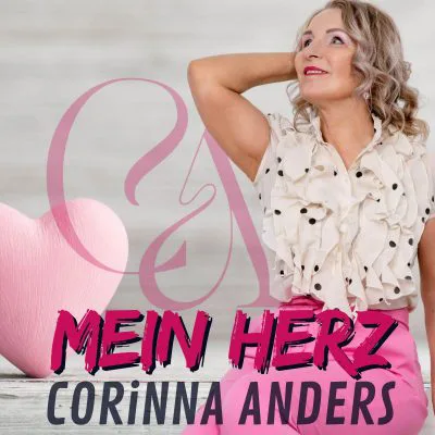 Eine Frau mit lockigem Haar in einer cremefarbenen Rüschenbluse und rosafarbenen Hosen posiert neben einem großen rosafarbenen Herz und verkörpert den Geist von „Mein Herz“. Der Hintergrund ist hellgrau, während der markante Text den Charme und das Talent der Schlagersängerin Corinna Anders hervorhebt.