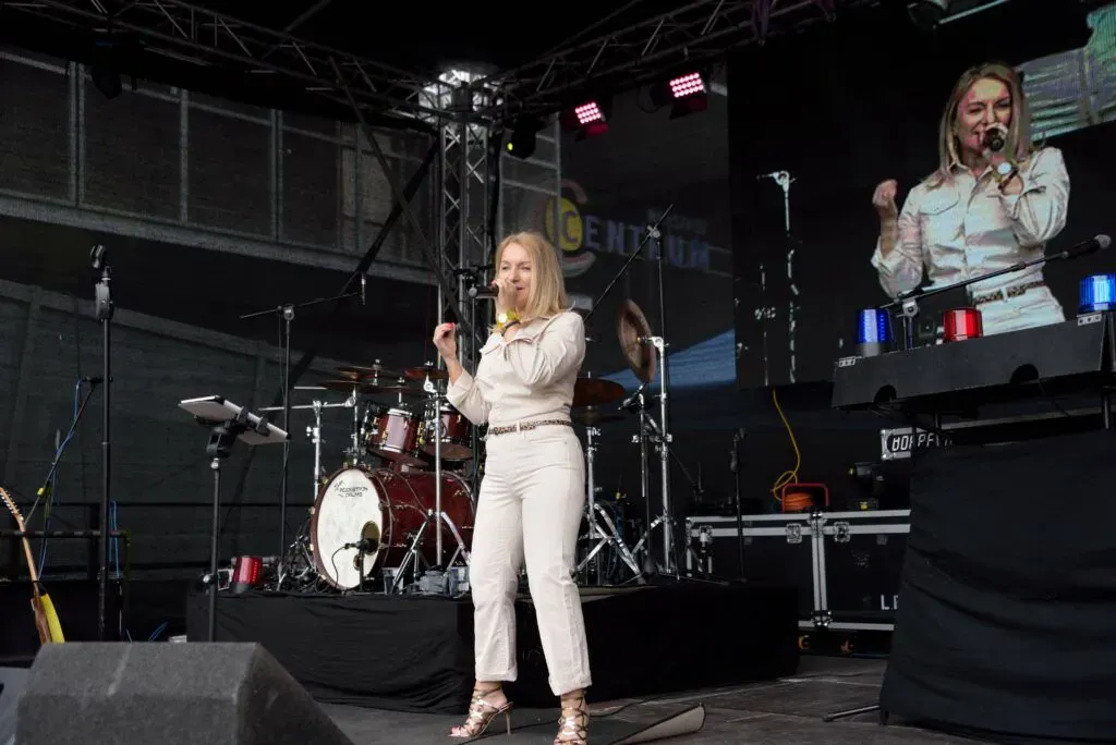Eine Schlagersängerin stellt ihr Talent unter Beweis, als sie auf der Bühne einer Outdoor-Veranstaltung singt.