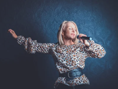 Schlagersängerin Corinna Anders tritt im Leoparden-Shirt auf und singt in ein Mikrofon.